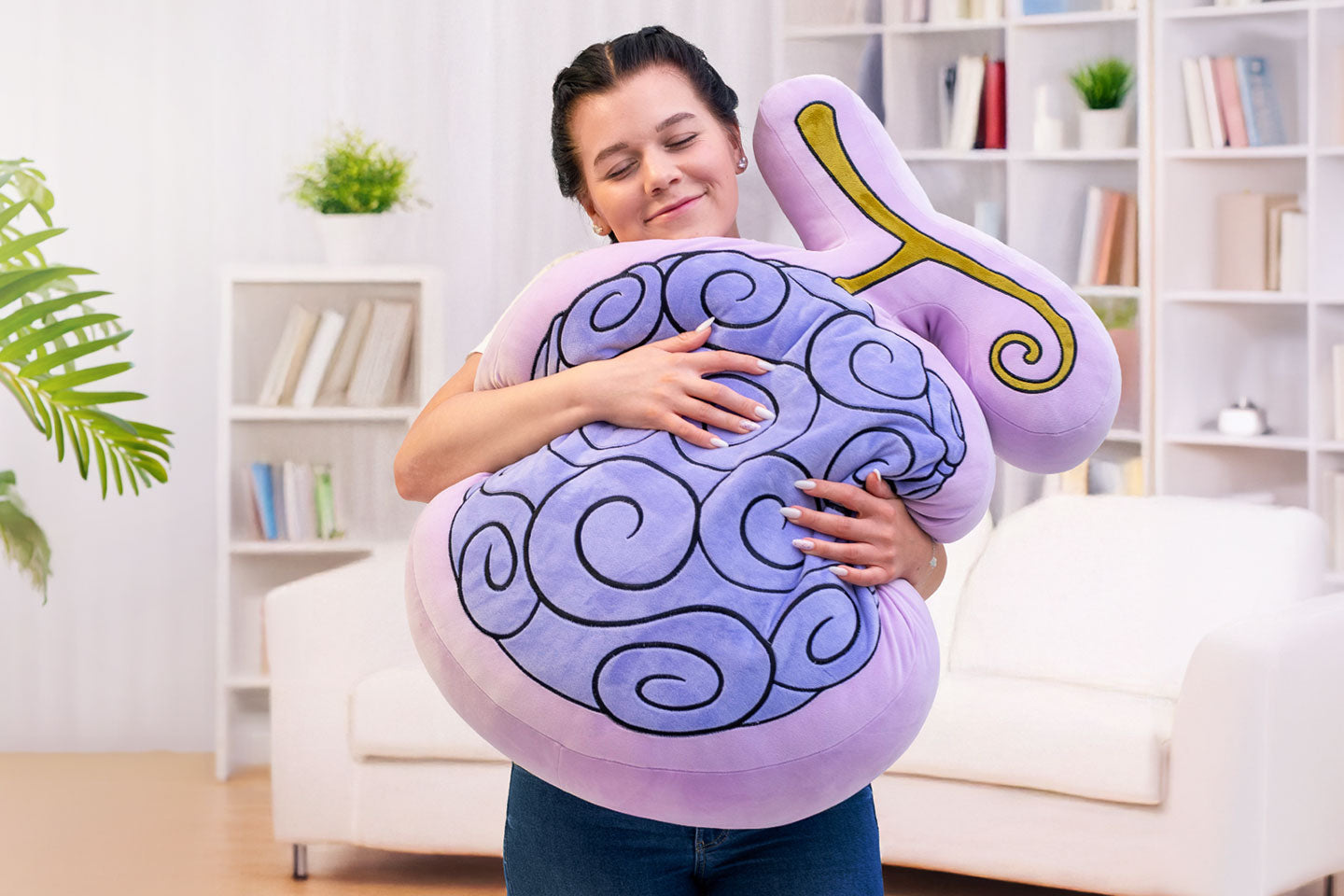 Person umarmt ein großes lilafarbenes One Piece Gomu Gomu Teufelsfrucht XXL Kissen mit typischem Spiralmuster und geschwungenem Stiel in einem hellen Wohnzimmer.